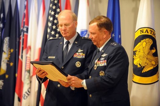 A photograph of 2 members of the Armed Forces reviewing a certificate.