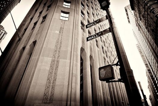 A black and white photo of a building with a Wall Street street sign.