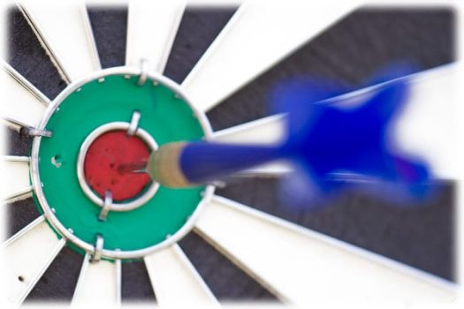 A photograph of a dartboard with an blue dart in the bullseye.