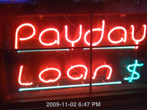 A photograph of a neon sign that says "Payday Loans."