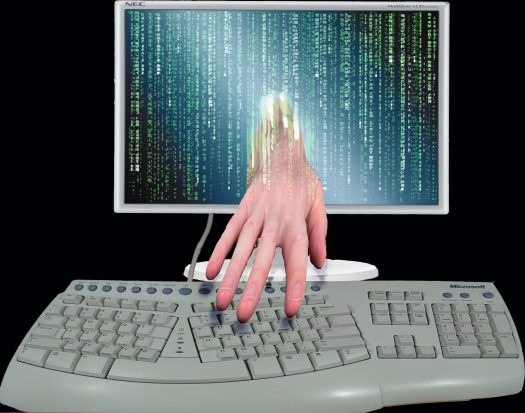 A hand reaching out of a computer monitor, hovering over an erognomic keyboard
