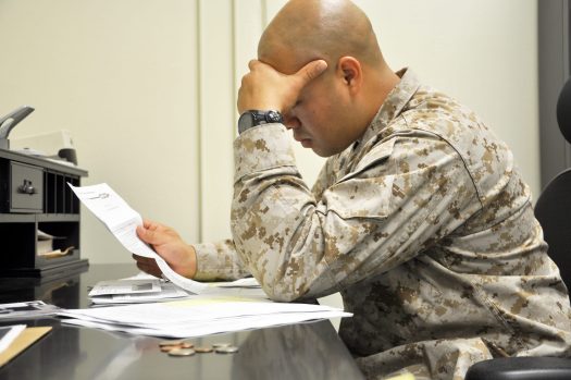 Service member, stressed, looking at paperwork