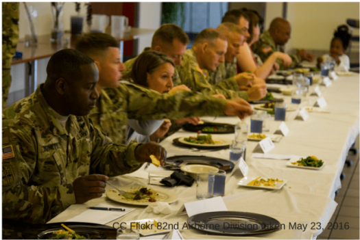 Military service members eating food at long table