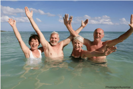 Four senior adults in the water, holding their hands up