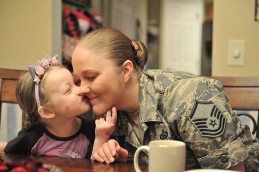 Young girl kisses her mother, who is a service member