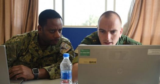 Two military service members looking at a laptop
