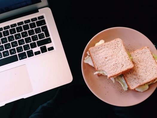 Sandwiches on a plate next to a laptop