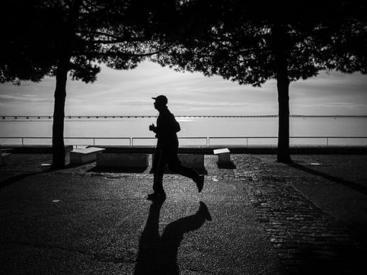 Silhouette of a man running next to a body of water