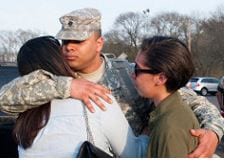 Service member embracing female and youth