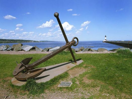 Anchor statue by a body of water