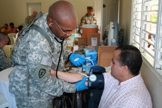 Military doctor checks a man's blood pressure