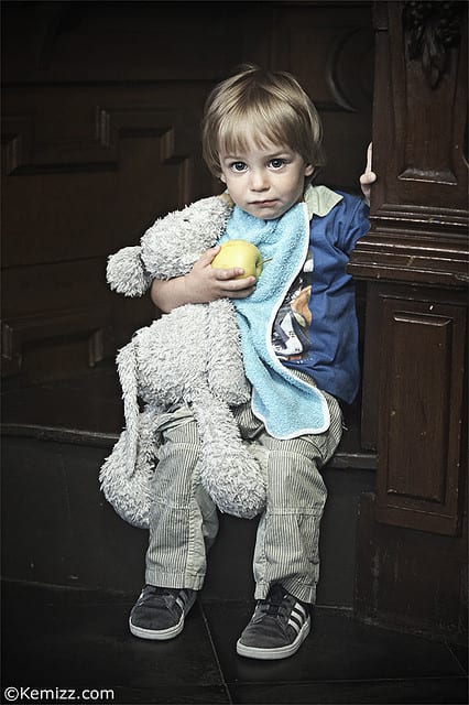 Little boy holding teddy bear and apple