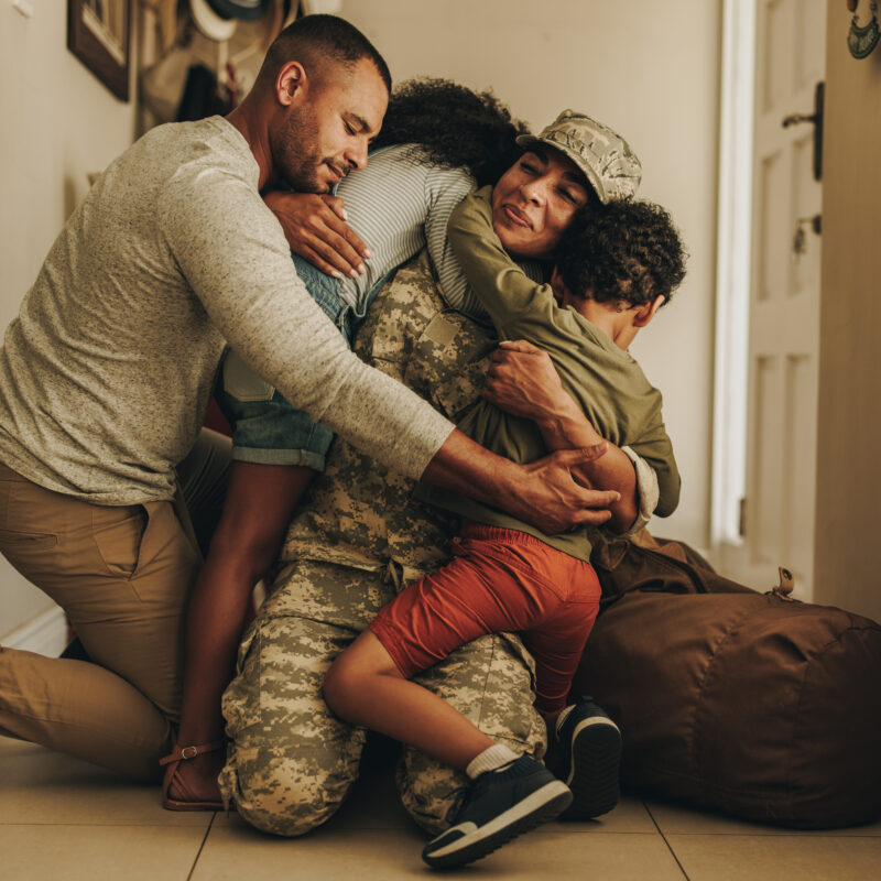 Happy military homecoming. Female soldier reuniting with her husband and children after serving in the army. Cheerful servicewoman embracing her family after returning home from deployment.