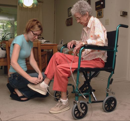 Elderly woman receiving help from a caregiver.