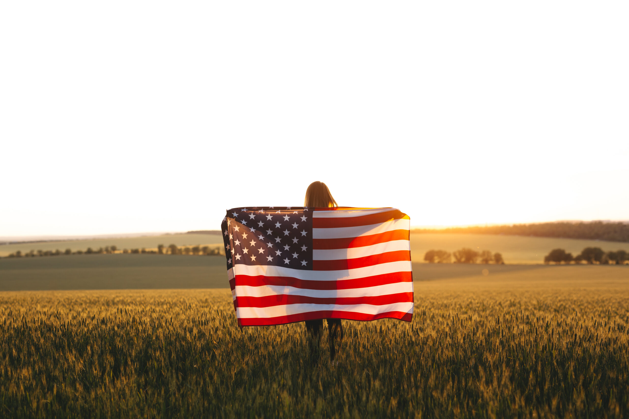 Girl with American flag in field.
