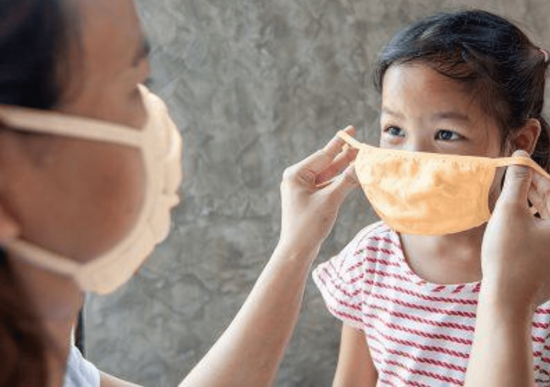 mother helping child put mask on