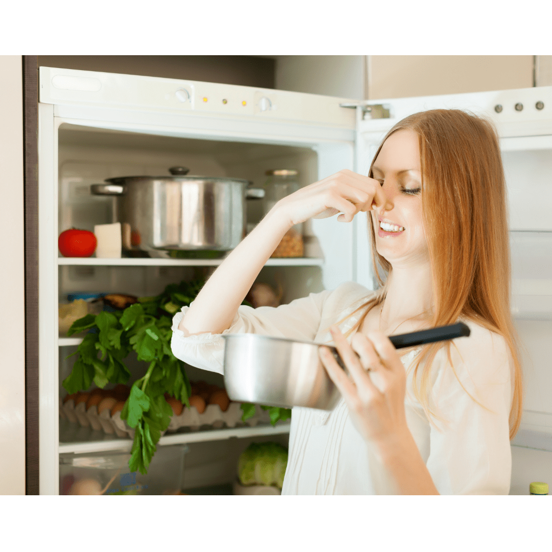 Woman in refrigerator smelling expired food
