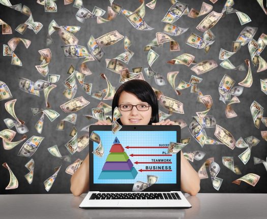 Woman holding laptop with hundred- and fifty-dollar bills raining down around her