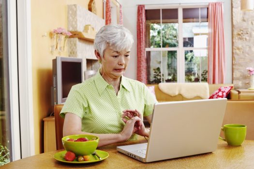 Senior woman grimacing at laptop screen