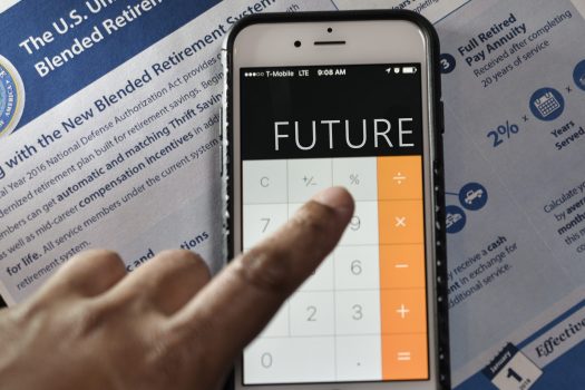 A photo of a finger poised over a smartphone, who's calculator screen spells out future.