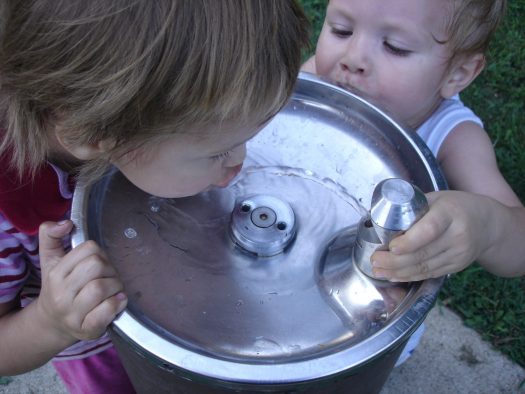 Two young children at a water fountain