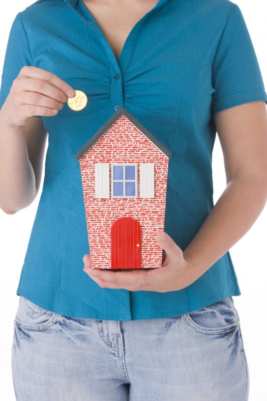 Woman holding cardboard house and coin