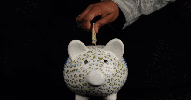 Hand inserting money into piggy bank