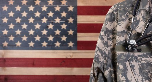 Service member wearing stethoscope against American flag painted on wooden background