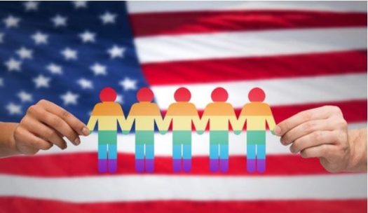 Hands holding rainbow-colored paper doll chain against American flag background
