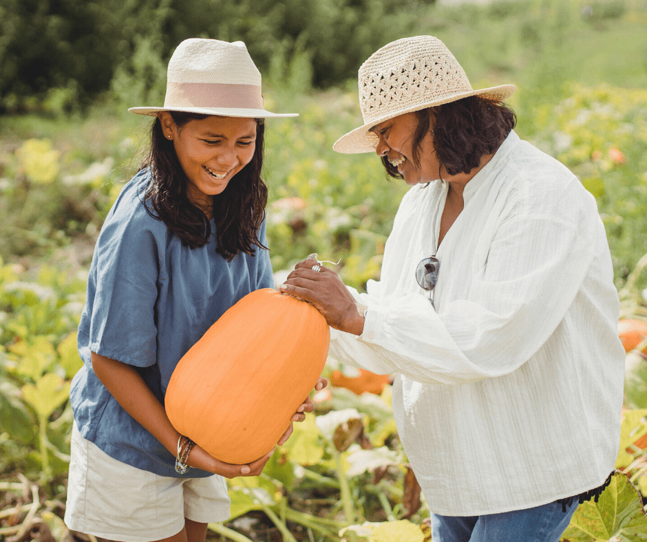 Happy woman and daughter holding pumpkin in field