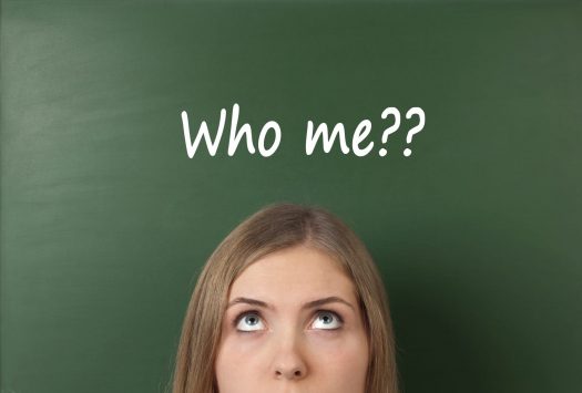 Woman looking up at the words "Who me??" written on a chalkboard