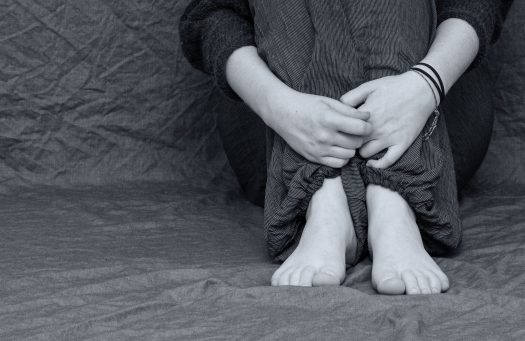 A young person holding their knees to their chest