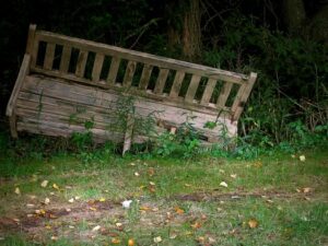 Picture of a broken wooden bench, falling onto the ground
