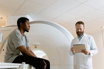 Doctor talking with patient in front of MRI machinet