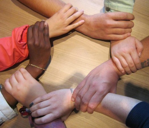 hands of multiple people clasped together for support