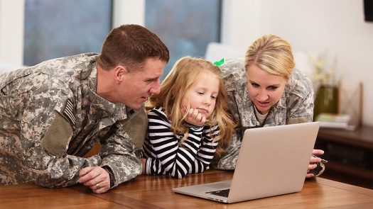 Military parents looking at laptop with young daughter