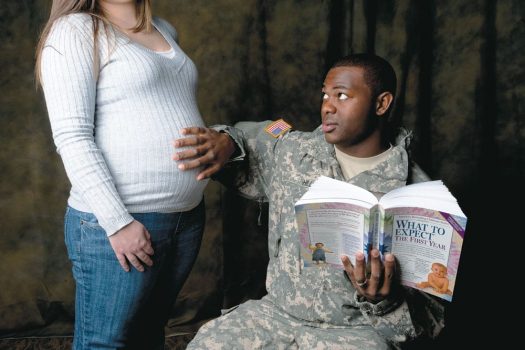 Military dad with hand on pregnant woman's belly