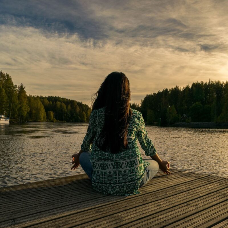 Woman in yoga pose on a dock lake