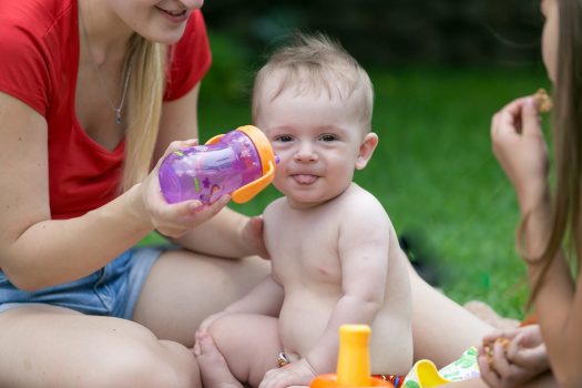 Woman holding sippy cup up to baby's face