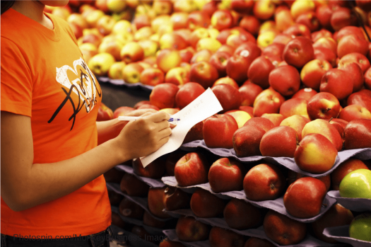 Woman taking notes while looking at apples at the store