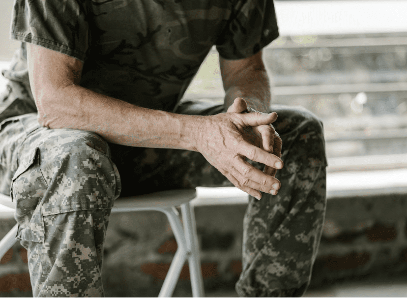 Solider sitting with hands touching.