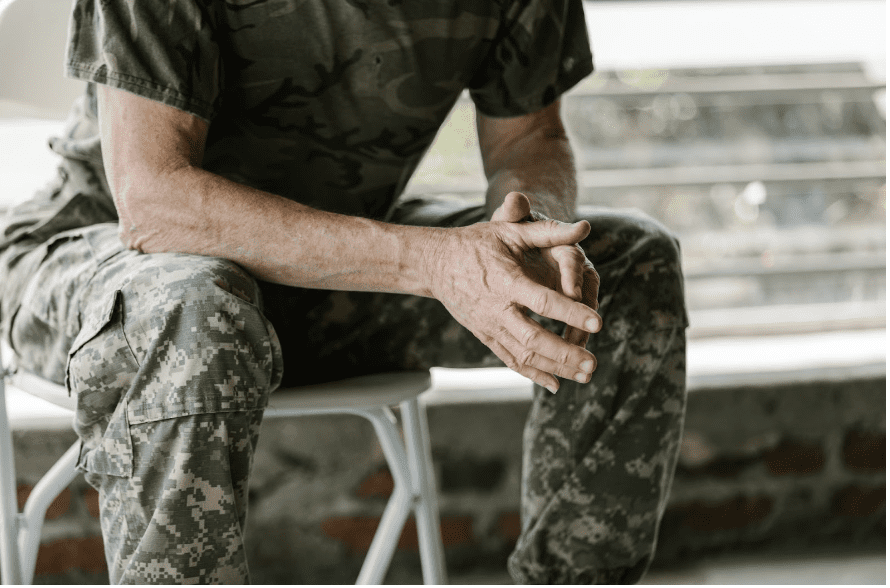 Solider sitting with hands touching.