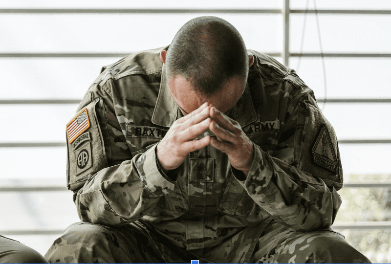 Male solider sitting with his head in his hands