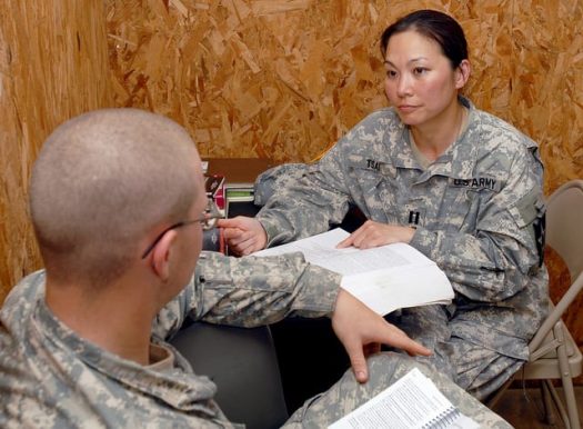 Picture of army medicine psychologist sitting at a desk talking to another army service member