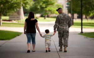 Military couple walking holding hands with small child