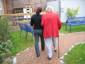 Young woman assisting elderly woman with cane