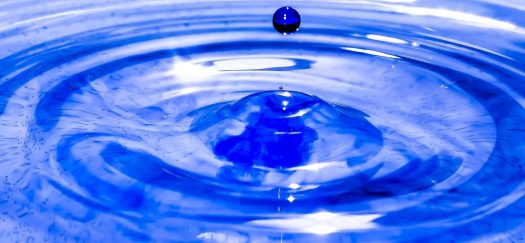 Blue water droplet making ripples