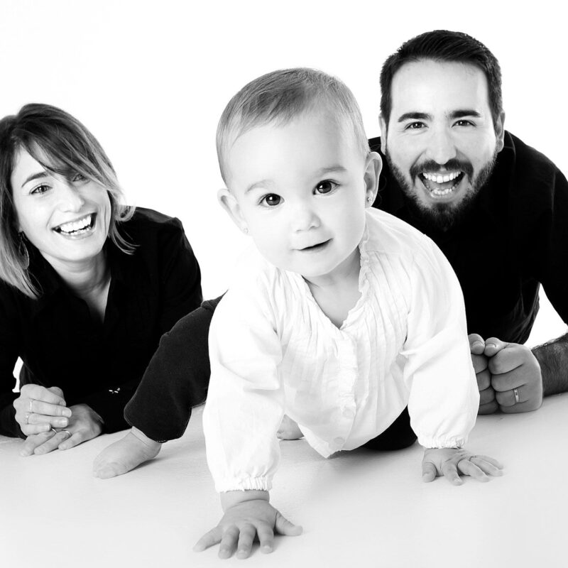 black and white photo of excited man and woman on floor with baby crawling