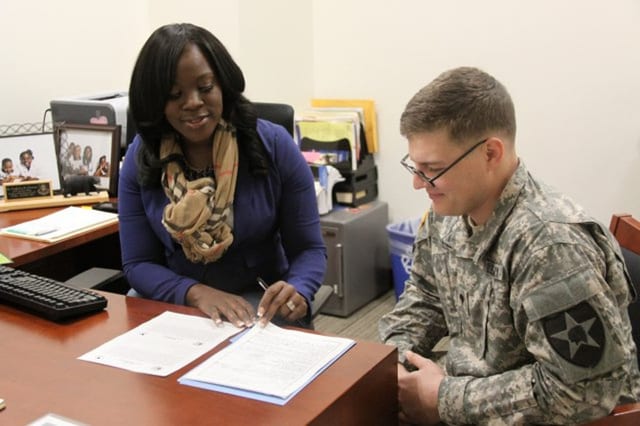 A woman is counseling a service member at a desk.
