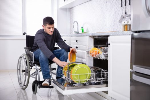 Handicapped Man Arranging Plates In Dishwasher